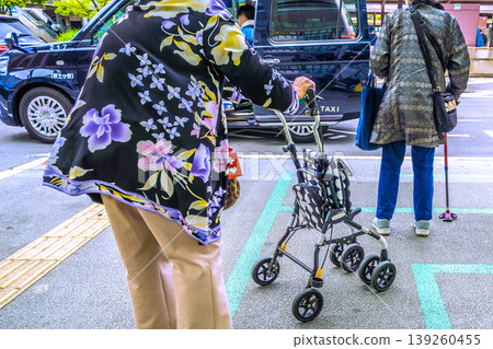 日本橫濱的城市景觀:老化社會…一位戴著口罩的老婦人在橫濱市的計程車站等計程車。 日本橫濱的城市景觀:老化社會…一位戴著口罩的老婦人在橫濱市的計程車站等計程車。 139260455
