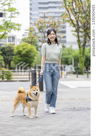一位年輕女子正在遛她的柴犬。 一位年輕女子正在遛她的柴犬。 139260485