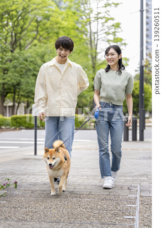 一對年輕男女牽著他們的柴犬散步。 一對年輕男女牽著他們的柴犬散步。 139260511