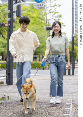 A young man and woman walking their Shiba Inu. 139260516