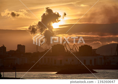 A gijon sunset obscured by industrial smoke, casting a dramatic silhouette A gijon sunset obscured by industrial smoke, casting a dramatic silhouette 139260647