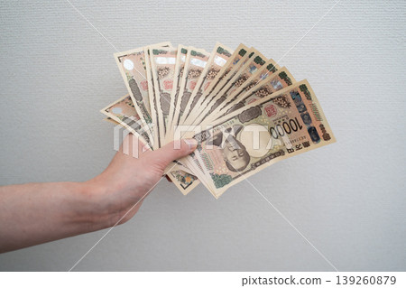 A woman's hands spreading money against a white background. A woman's hands spreading money against a white background. 139260879