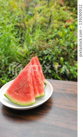 A plate of chilled watermelon, cut into five slices, enjoyed in the garden – a summer image. 139260912