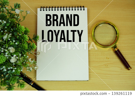 Brand Loyalty text written on notepad with magnifying glass flat lay on wooden background Brand Loyalty text written on notepad with magnifying glass flat lay on wooden background 139261119