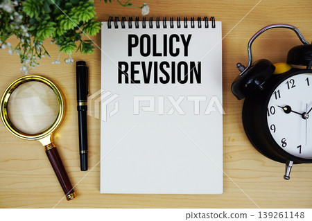Policy Revision text written on notepad with alarm clock and magnifying glass flat lay on wooden background 139261148