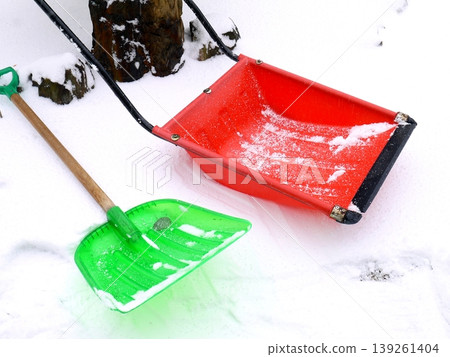 A red snow shovel and snow dumper placed on top of the accumulated snow. 139261404