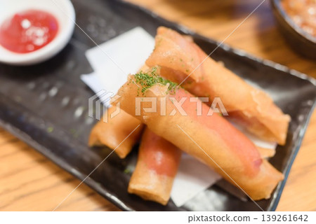 一份盛在黑色盤子裡的炸香腸小吃。 139261642