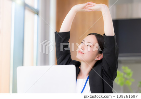 一位女商務人士在電腦前工作後,微笑地伸了個懶腰,休息片刻,提高了工作效率。 一位女商務人士在電腦前工作後,微笑地伸了個懶腰,休息片刻,提高了工作效率。 139261697
