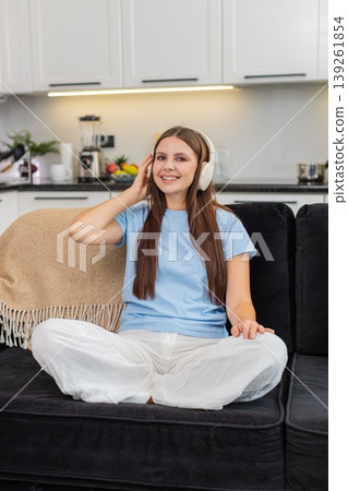 Young woman relaxes with wireless headphones listens to favorite music rests eyes calm and peaceful Young woman relaxes with wireless headphones listens to favorite music rests eyes calm and peaceful 139261854