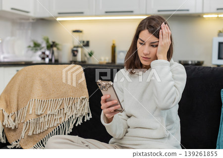 Young woman upset by negative alert on smartphone frowns whispers very anxious stress worried mood 139261855