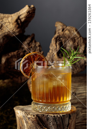 Old-fashioned cocktail with ice on an old wooden stump. Old-fashioned cocktail with ice on an old wooden stump. 139261864
