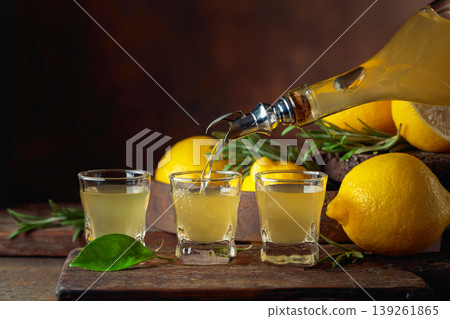 Italian liqueur Limoncello with fresh lemons and rosemary branches. Italian liqueur Limoncello with fresh lemons and rosemary branches. 139261865