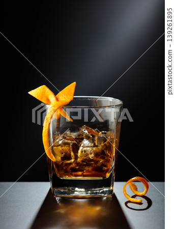 Old fashioned cocktail in a sweating glass on a black table. Old fashioned cocktail in a sweating glass on a black table. 139261895