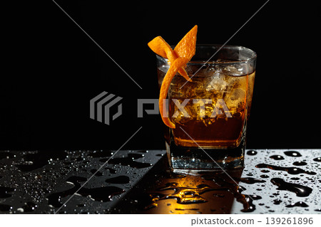 Old fashioned cocktail on a wet black table. Old fashioned cocktail on a wet black table. 139261896