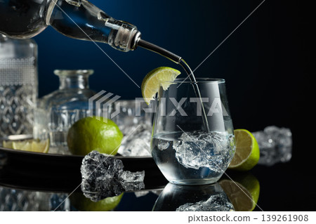 Gin is poured into a glass with ice. Gin is poured into a glass with ice. 139261908