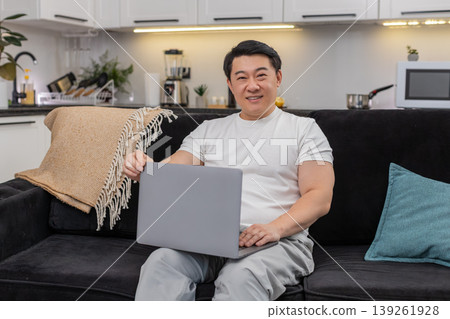 Asian man launches laptop for work logs in types quickly smiles with confidence ready to start tasks Asian man launches laptop for work logs in types quickly smiles with confidence ready to start tasks 139261928