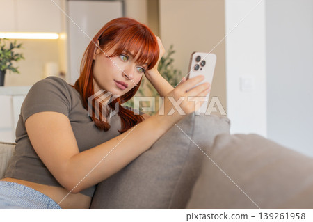 Young woman tires of endless news feed on smartphone bored annoyed low energy and mental drain mood 139261958