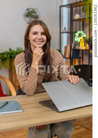 Young woman closes laptop with relief smiles as project is sent and work finished milestone reached 139261962