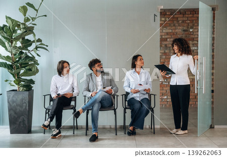 A woman walked out, calling someone. People near the wall, waiting for a job interview, potential workers A woman walked out, calling someone. People near the wall, waiting for a job interview, potential workers 139262063