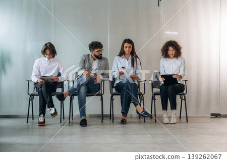Preparing, nervous. People near the wall, waiting for a job interview, potential workers Preparing, nervous. People near the wall, waiting for a job interview, potential workers 139262067