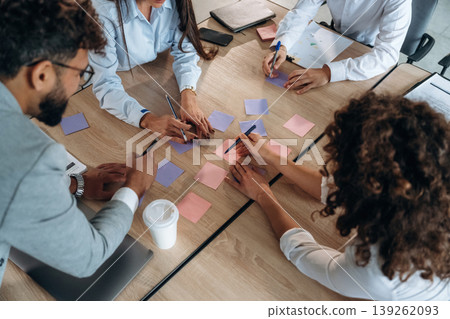 Brainstorming process. Office workers are by the table with paper stickers Brainstorming process. Office workers are by the table with paper stickers 139262093