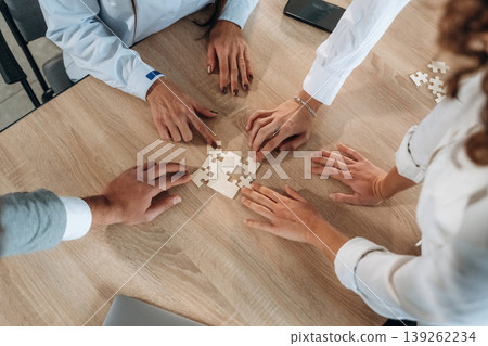 Focused top view of office workers that are playing puzzle game, conception of success Focused top view of office workers that are playing puzzle game, conception of success 139262234