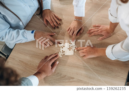 Focused top view of office workers that are playing puzzle game, conception of success Focused top view of office workers that are playing puzzle game, conception of success 139262235