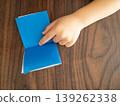 A child's hand pointing to the folds of blue origami paper. 139262338