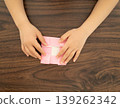 A child's hands folding origami on a wooden table 139262342