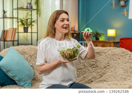 Pregnant woman eats fresh vitamin salad with cabbage tomato smiles enjoys healthy meal at home sofa Pregnant woman eats fresh vitamin salad with cabbage tomato smiles enjoys healthy meal at home sofa 139262586