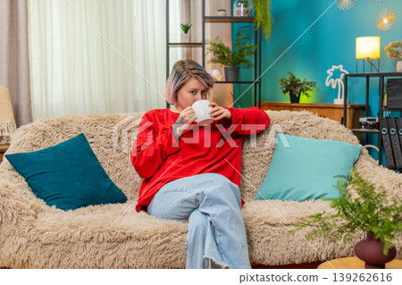 Woman enjoying drinking coffee sitting comfortably on sofa relaxed satisfied calm leisure expression Woman enjoying drinking coffee sitting comfortably on sofa relaxed satisfied calm leisure expression 139262616