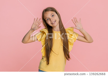 Child girl kid happily waving and smiling hello in playful mood, greeting someone in front of camera 139262668