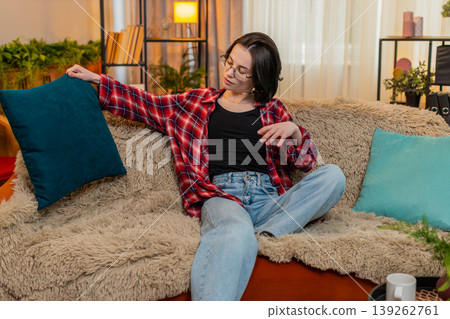 Smiling woman arranging decorative pillows at home, satisfaction while admiring clean living space Smiling woman arranging decorative pillows at home, satisfaction while admiring clean living space 139262761