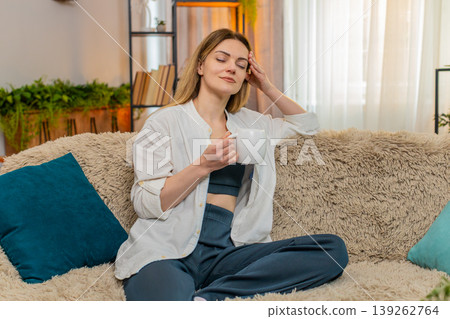 Adult woman drinking tea at home in the morning, calm expression, peaceful and relaxing moment Adult woman drinking tea at home in the morning, calm expression, peaceful and relaxing moment 139262764