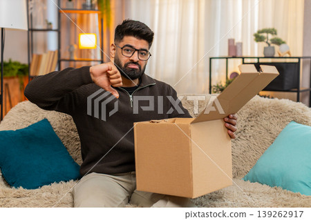 Indian man on sofa opens box and shakes head after discovering wrong item in online delivery order Indian man on sofa opens box and shakes head after discovering wrong item in online delivery order 139262917