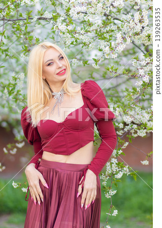 Smiling Blonde Woman In Burgundy Outfit Near Blossoms Smiling Blonde Woman In Burgundy Outfit Near Blossoms 139263535