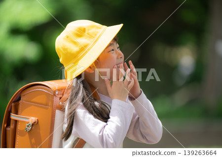 A schoolgirl in a backpack shows a surprised expression amidst the fresh greenery. A scene of elementary school students going to school: surprise, realization, excitement. A schoolgirl in a backpack shows a surprised expression amidst the fresh greenery. A scene of elementary school students going to school: surprise, realization, excitement. 139263664