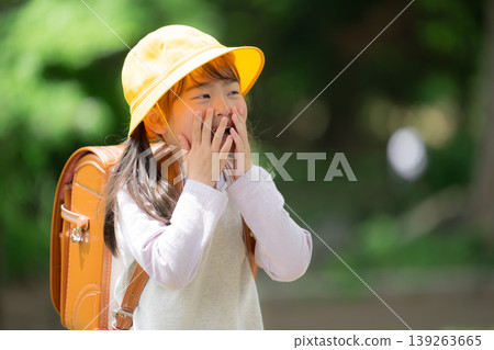 A schoolgirl in a backpack shows a surprised expression amidst the fresh greenery. A scene of elementary school students going to school: surprise, realization, excitement. A schoolgirl in a backpack shows a surprised expression amidst the fresh greenery. A scene of elementary school students going to school: surprise, realization, excitement. 139263665