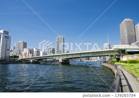 View of Tsukuda Bridge and the surrounding cityscape from the Sumida River promenade, Chuo Ward, Tokyo. View of Tsukuda Bridge and the surrounding cityscape from the Sumida River promenade, Chuo Ward, Tokyo. 139263784