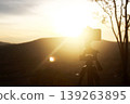 Sunset Serenity: A lone tripod stands tall, framing a breathtaking sunset with golden hues. Capturing a moment of solitude. 139263895