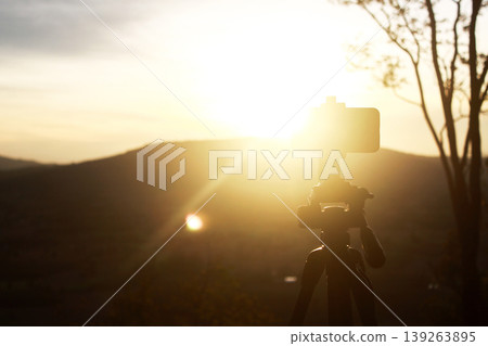 Sunset Serenity: A lone tripod stands tall, framing a breathtaking sunset with golden hues. Capturing a moment of solitude. Sunset Serenity: A lone tripod stands tall, framing a breathtaking sunset with golden hues. Capturing a moment of solitude. 139263895