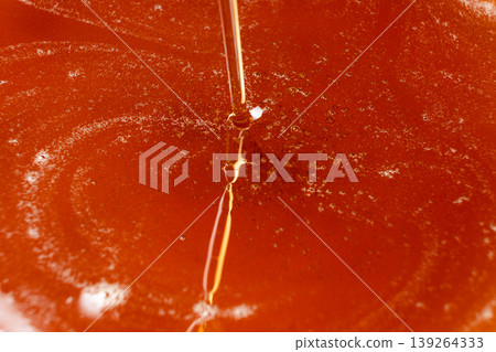 Thick stream of golden maple syrup pouring down Thick stream of golden maple syrup pouring down 139264333