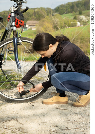 Woman connecting a pump to a bicycle tire at a repair station. Woman connecting a pump to a bicycle tire at a repair station. 139264369