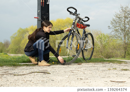 Female cyclist using a public bike maintenance point. Female cyclist using a public bike maintenance point. 139264374