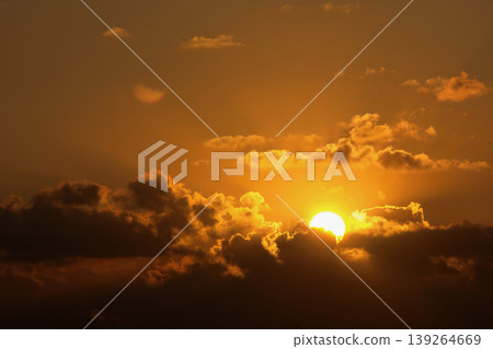 Dramatic Sunset Sky with Golden Sun and Dark Clouds. Intense, beautiful nature background. Dramatic Sunset Sky with Golden Sun and Dark Clouds. Intense, beautiful nature background. 139264669