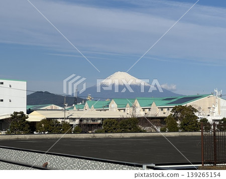 Mount Fuji, with its snow-capped peak, as seen over the buildings of the city. Mount Fuji, with its snow-capped peak, as seen over the buildings of the city. 139265154
