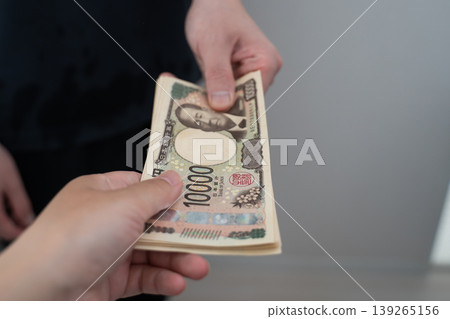 A hand handing over a wad of cash A hand handing over a wad of cash 139265156