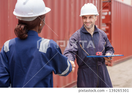Smiling mid-adult Caucasian male and Black female logistics professionals shaking hands at Asian shipping port. Smiling mid-adult Caucasian male and Black female logistics professionals shaking hands at Asian shipping port. 139265301