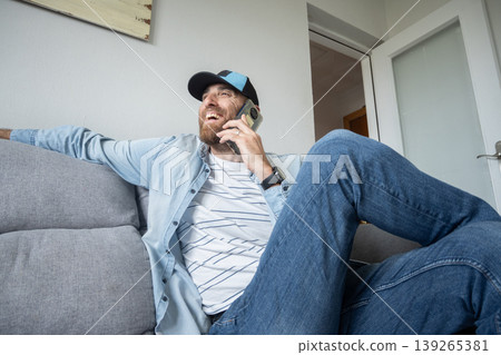 Man talking on smartphone sitting on sofa at home, casual lifestyle 139265381