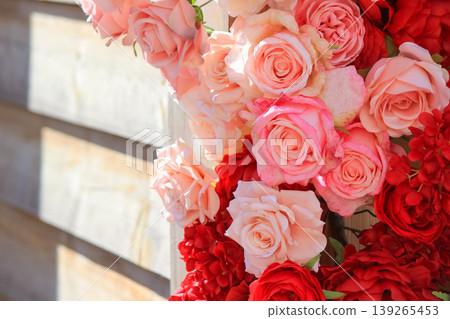 Beautiful arrangement of vibrant pink and red roses decorating a rustic wooden wall background 139265453